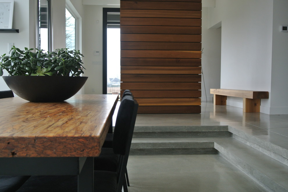 Photo of a contemporary dining room in Vancouver with white walls and concrete flooring.