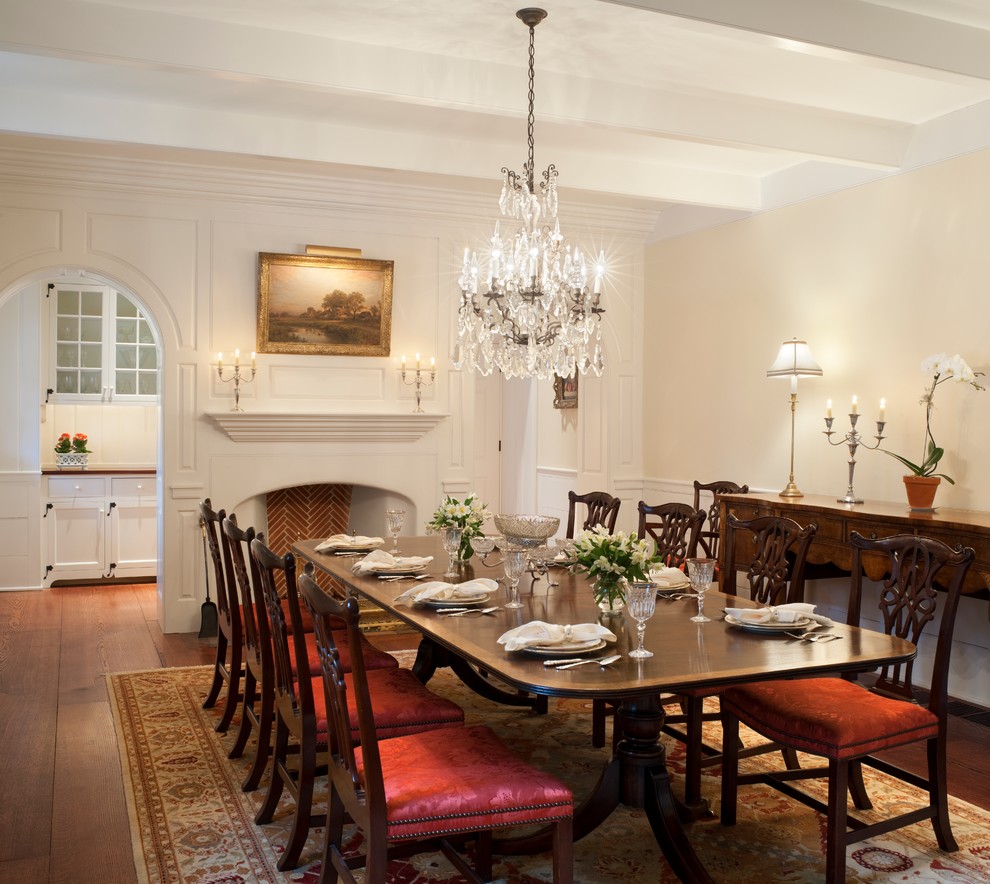 Inspiration pour une salle à manger traditionnelle avec un mur beige, parquet foncé et une cheminée standard.