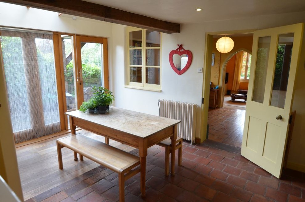 Modelo de comedor de cocina de estilo de casa de campo de tamaño medio con paredes blancas y suelo de baldosas de terracota