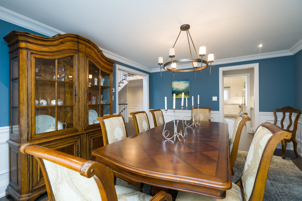 Cette photo montre une salle à manger fermée avec un mur bleu, parquet foncé, aucune cheminée, un sol marron et boiseries.