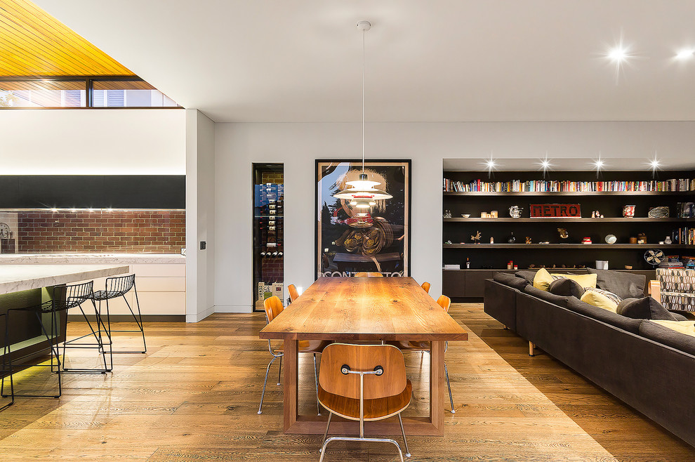 Immagine di una sala da pranzo aperta verso il soggiorno minimal con pareti bianche e pavimento in legno massello medio
