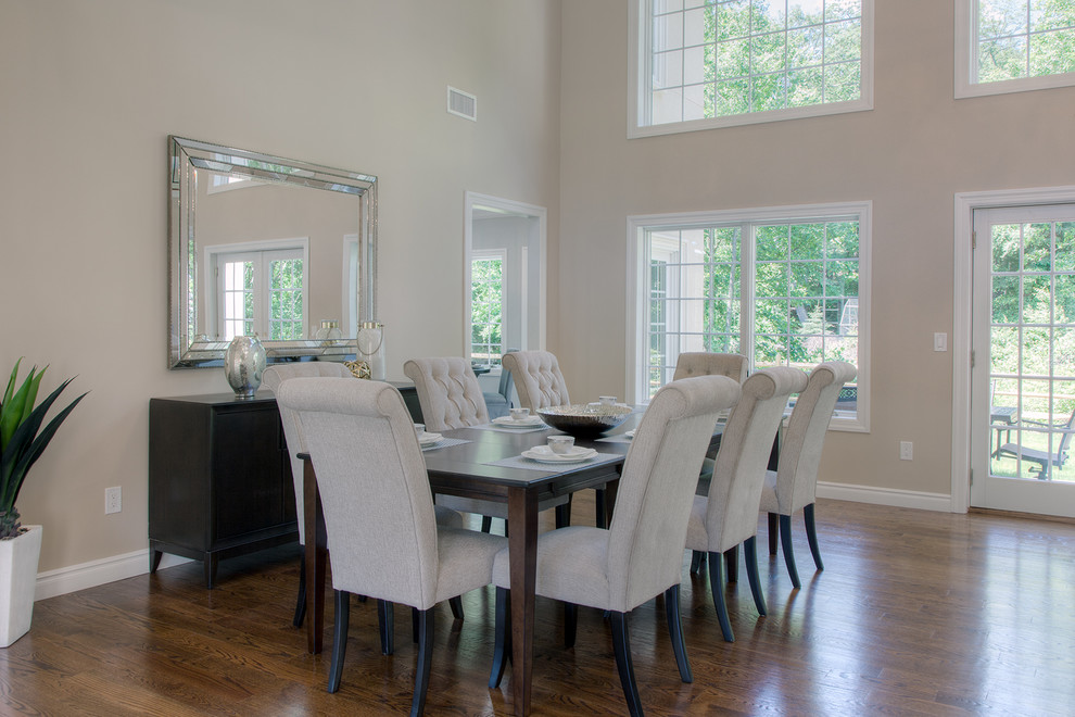 Cette image montre une grande salle à manger ouverte sur le salon traditionnelle avec un mur beige et un sol en bois brun.