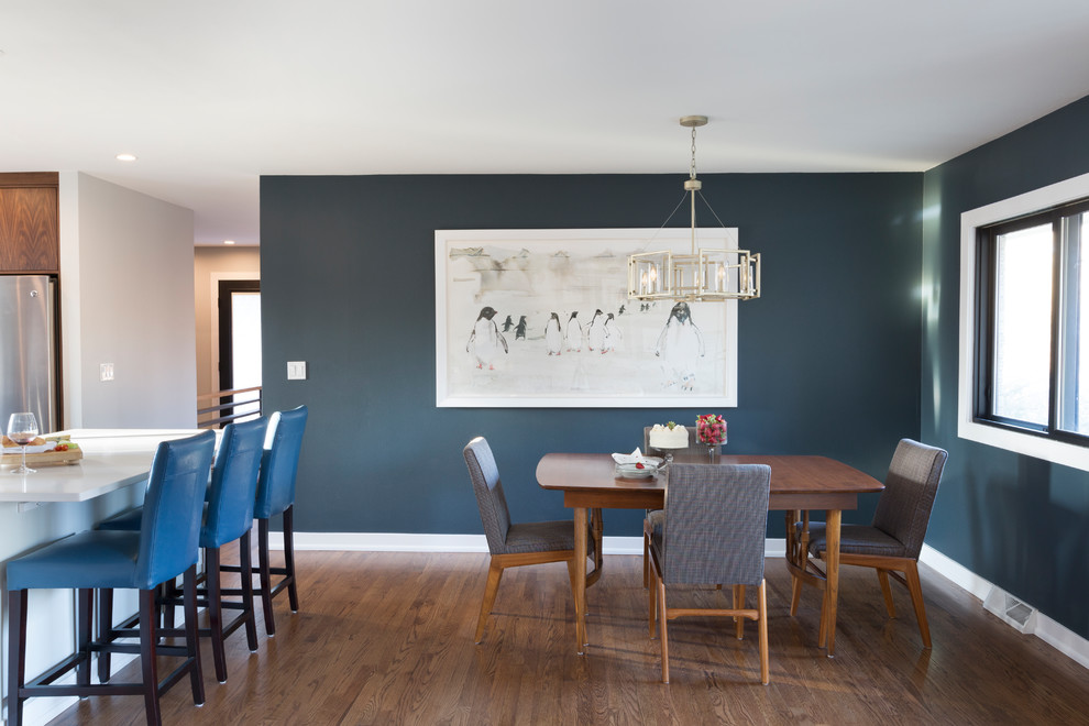 Aménagement d'une petite salle à manger ouverte sur la cuisine moderne avec un mur bleu, un sol en bois brun, aucune cheminée et un sol marron.