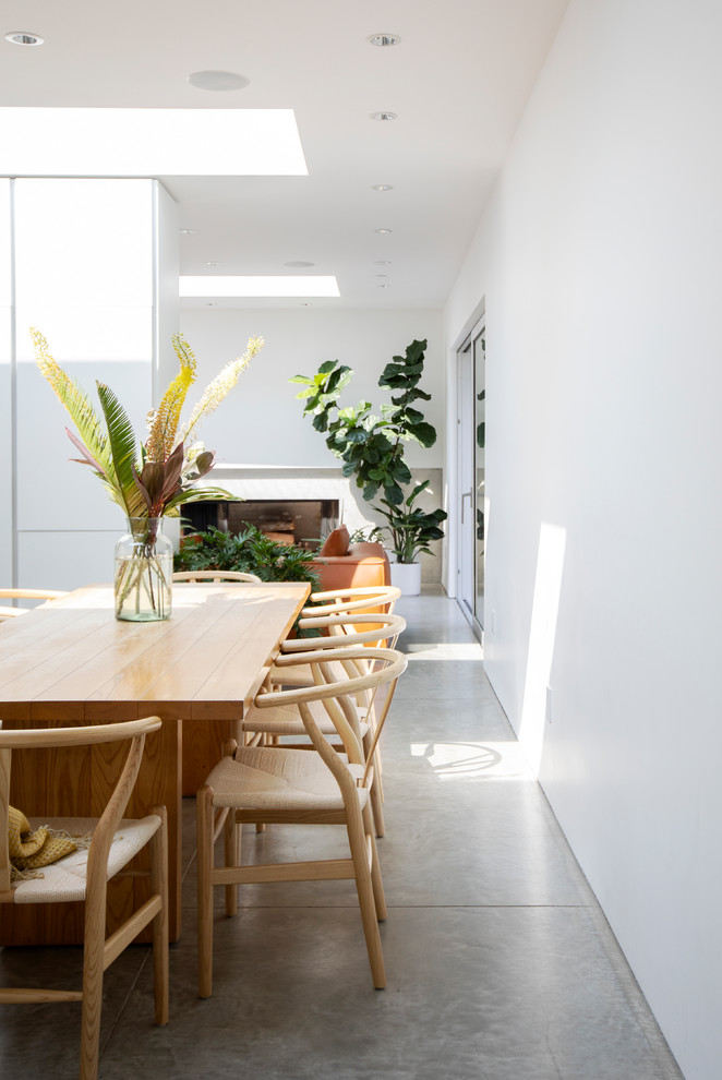 Exemple d'une salle à manger ouverte sur la cuisine tendance de taille moyenne avec un mur blanc, sol en béton ciré, un sol gris et aucune cheminée.
