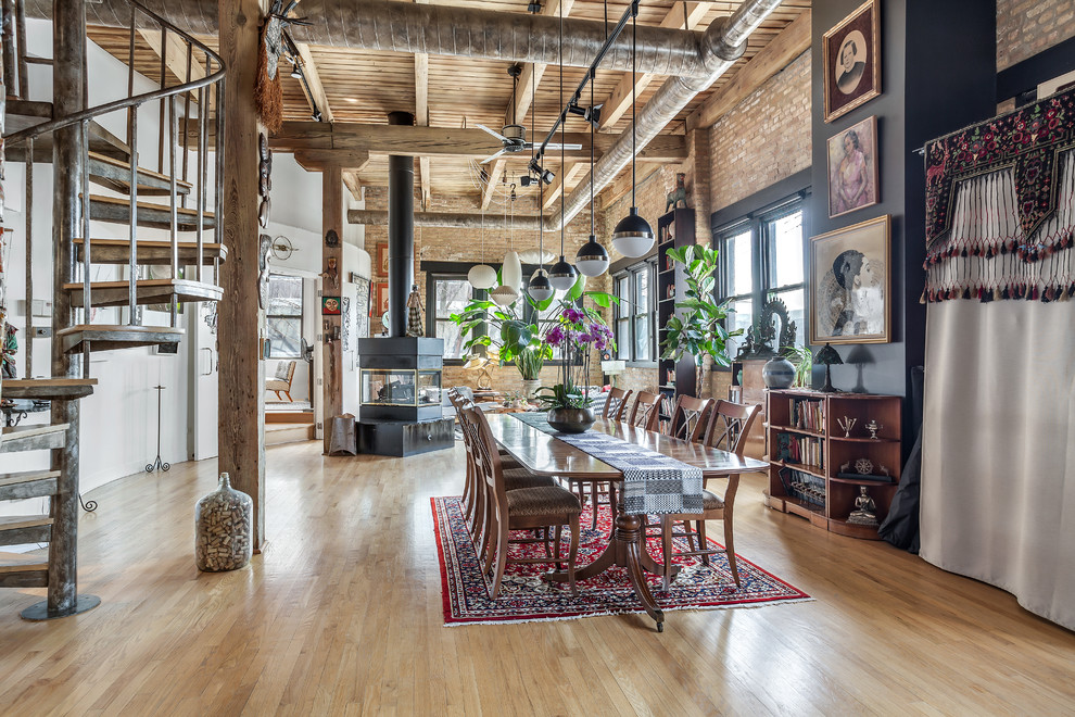 Immagine di una sala da pranzo aperta verso il soggiorno industriale di medie dimensioni con pareti multicolore, pavimento in legno massello medio, pavimento marrone e stufa a legna