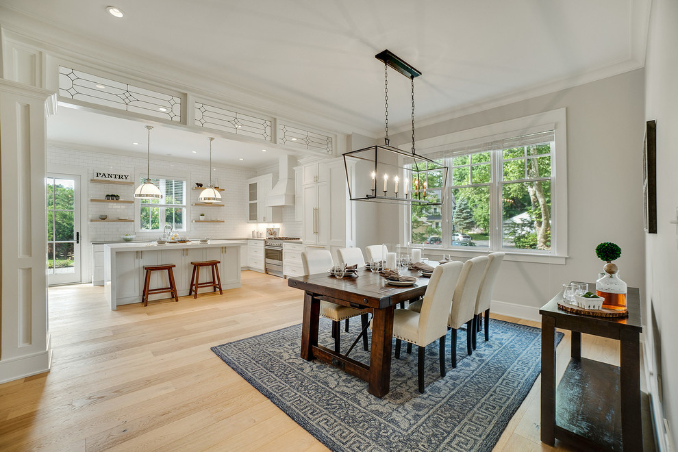 Foto di una sala da pranzo aperta verso la cucina country con pareti beige, parquet chiaro e pavimento beige