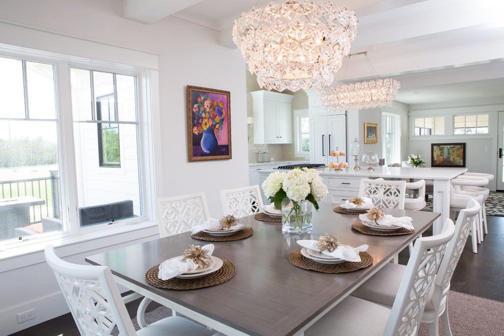 Cette photo montre une salle à manger ouverte sur le salon chic de taille moyenne avec un mur blanc, parquet foncé, une cheminée standard, un manteau de cheminée en pierre et un sol marron.