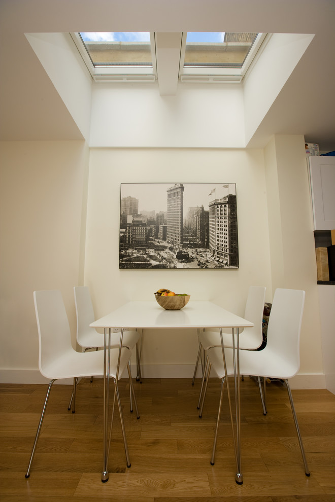 Inspiration pour une petite salle à manger ouverte sur la cuisine design avec un mur blanc et parquet clair.