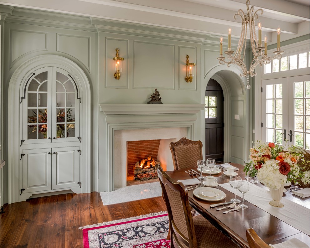 Idée de décoration pour une salle à manger tradition fermée avec un mur vert, un sol en bois brun, une cheminée standard et un manteau de cheminée en plâtre.