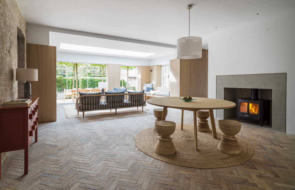 Ispirazione per una sala da pranzo minimal con pareti bianche, pavimento in mattoni, stufa a legna e pavimento marrone