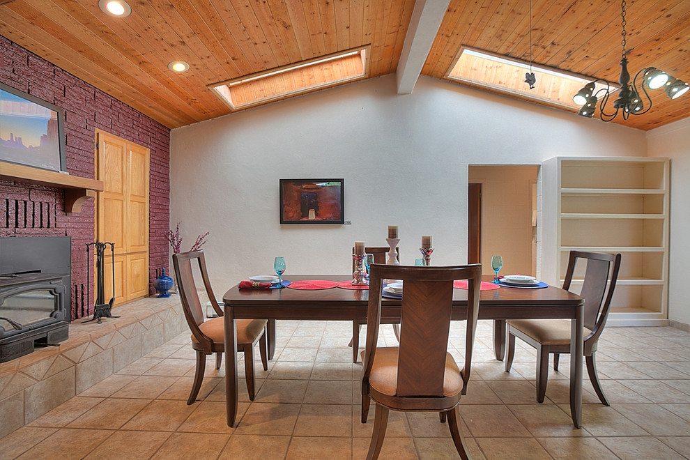 アルバカーキにある高級な広いサンタフェスタイルのおしゃれなダイニングキッチン (白い壁、磁器タイルの床、標準型暖炉、レンガの暖炉まわり) の写真
