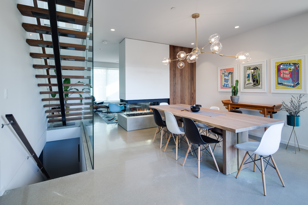 Источник вдохновения для домашнего уюта: кухня-столовая среднего размера в современном стиле с белыми стенами, бетонным полом, двусторонним камином, серым полом и фасадом камина из бетона