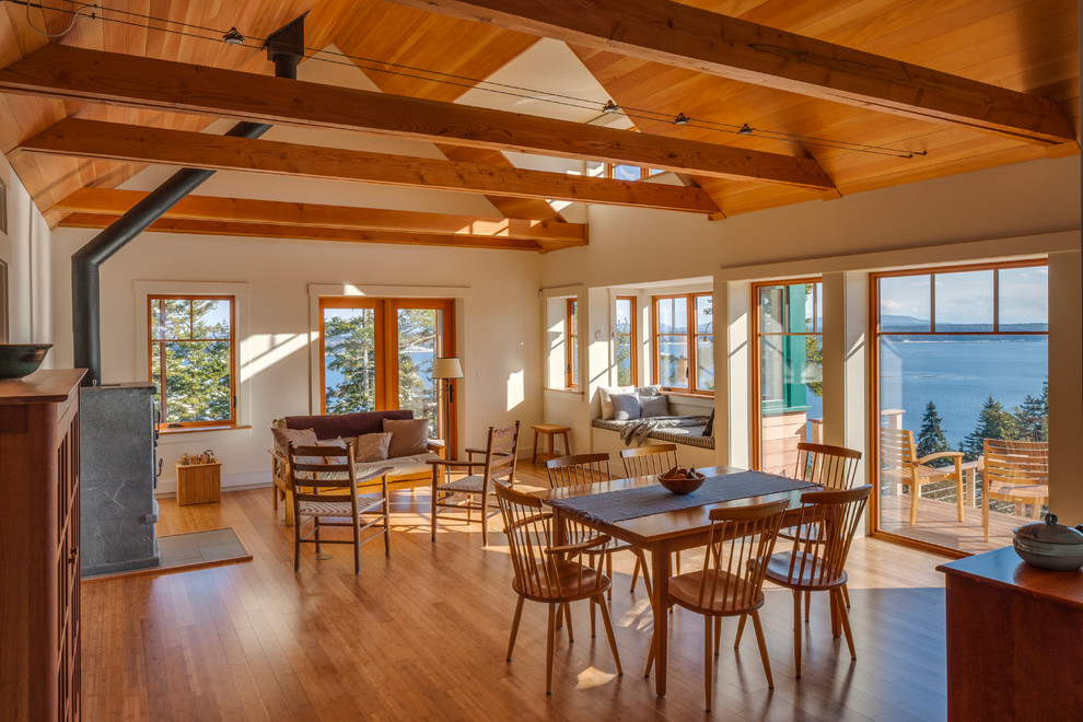 Foto di una sala da pranzo aperta verso il soggiorno stile rurale con pareti beige, pavimento in legno massello medio e stufa a legna