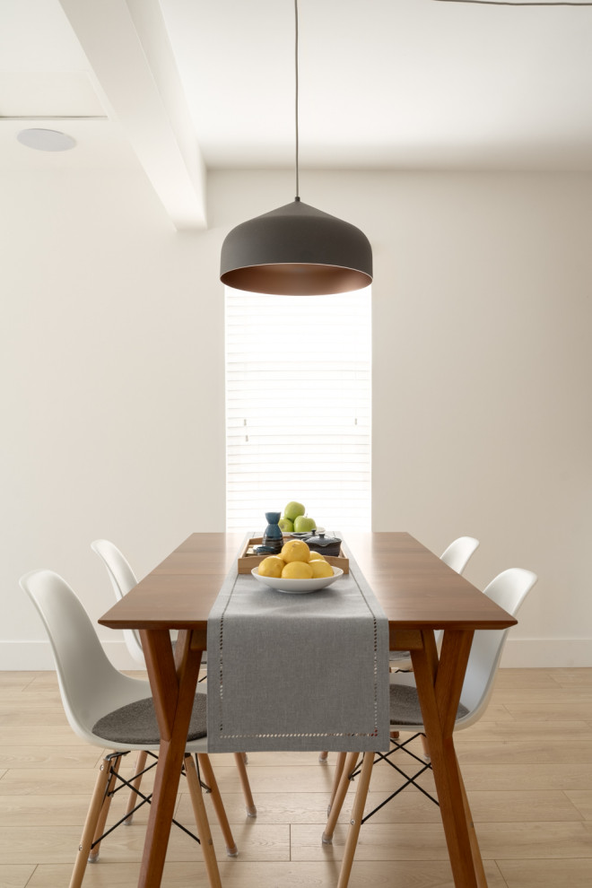 Esempio di una sala da pranzo aperta verso la cucina minimalista di medie dimensioni con pareti bianche, parquet chiaro e pavimento giallo