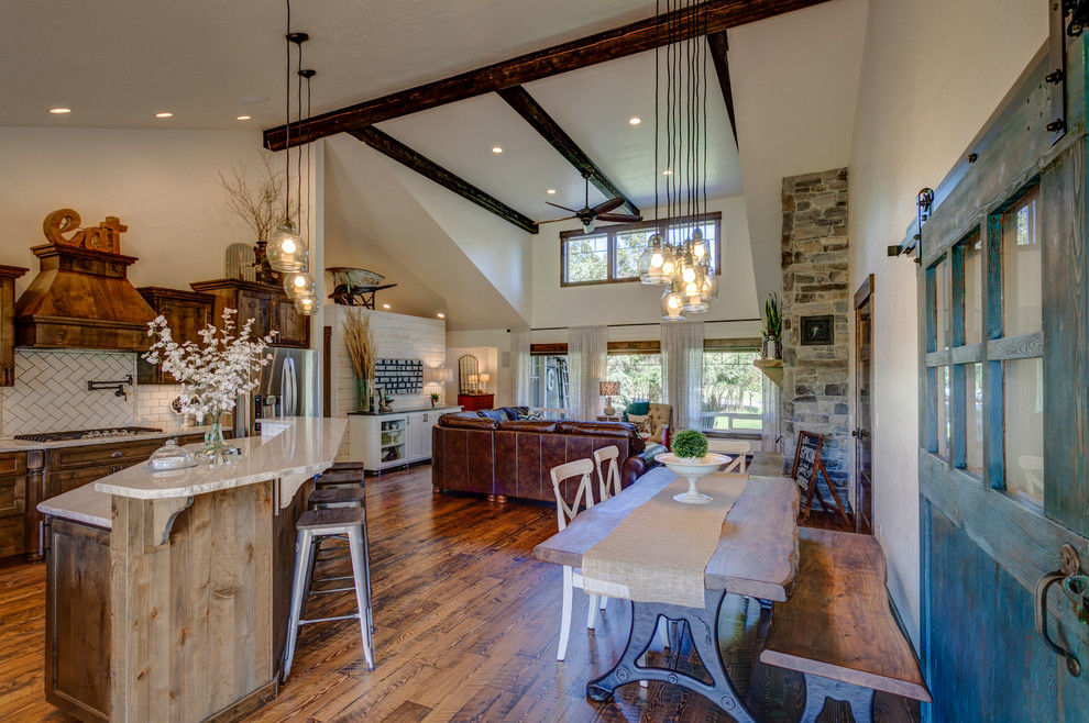 Exemple d'une salle à manger ouverte sur la cuisine montagne de taille moyenne avec un mur blanc, un sol en bois brun, une cheminée standard et un manteau de cheminée en pierre.