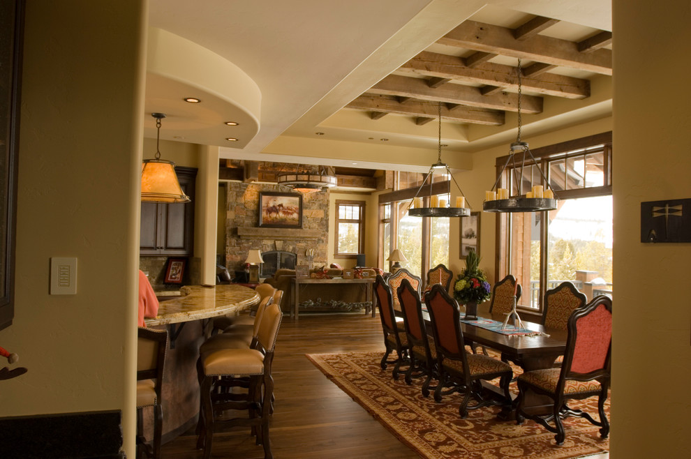 Aménagement d'une salle à manger montagne avec un sol en bois brun, une cheminée standard et un manteau de cheminée en plâtre.