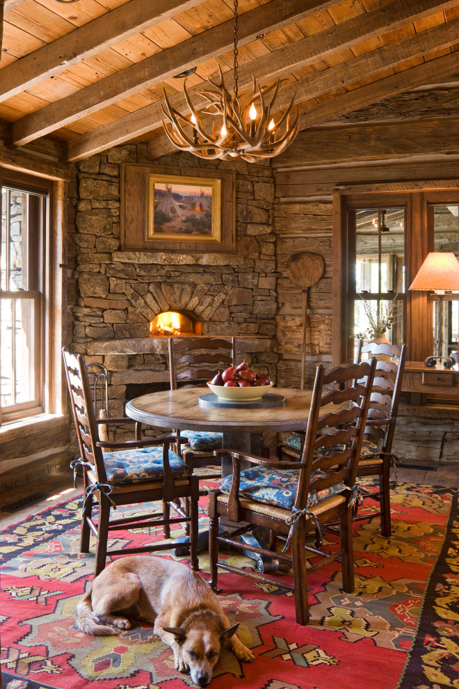 Idée de décoration pour une salle à manger chalet avec un manteau de cheminée en pierre, une cheminée d'angle et éclairage.