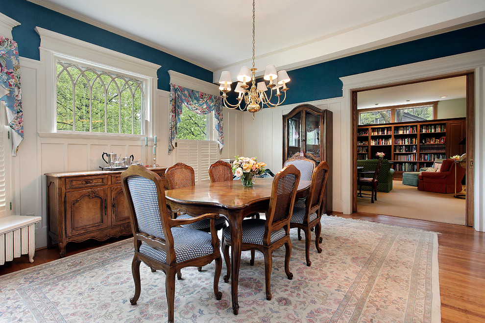 Cette image montre une salle à manger traditionnelle fermée avec un mur bleu et un sol en bois brun.