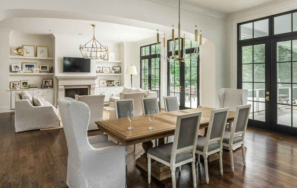 This is an example of a large classic open plan dining room in Nashville with white walls, dark hardwood flooring, a standard fireplace, a stone fireplace surround and brown floors.