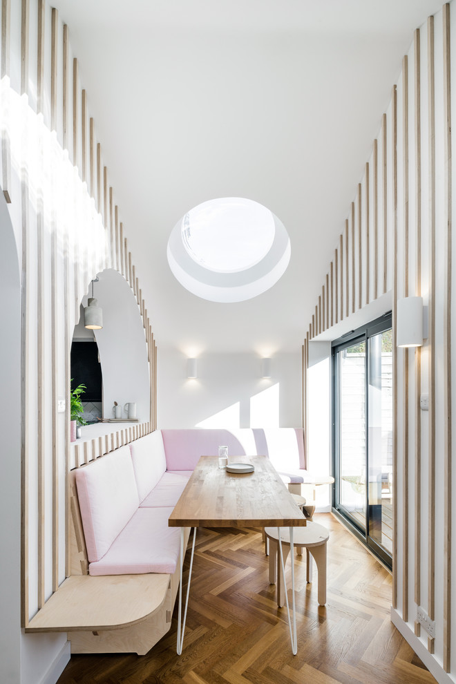 Cette photo montre une salle à manger ouverte sur le salon tendance de taille moyenne avec un sol en bois brun, un sol marron et un mur multicolore.