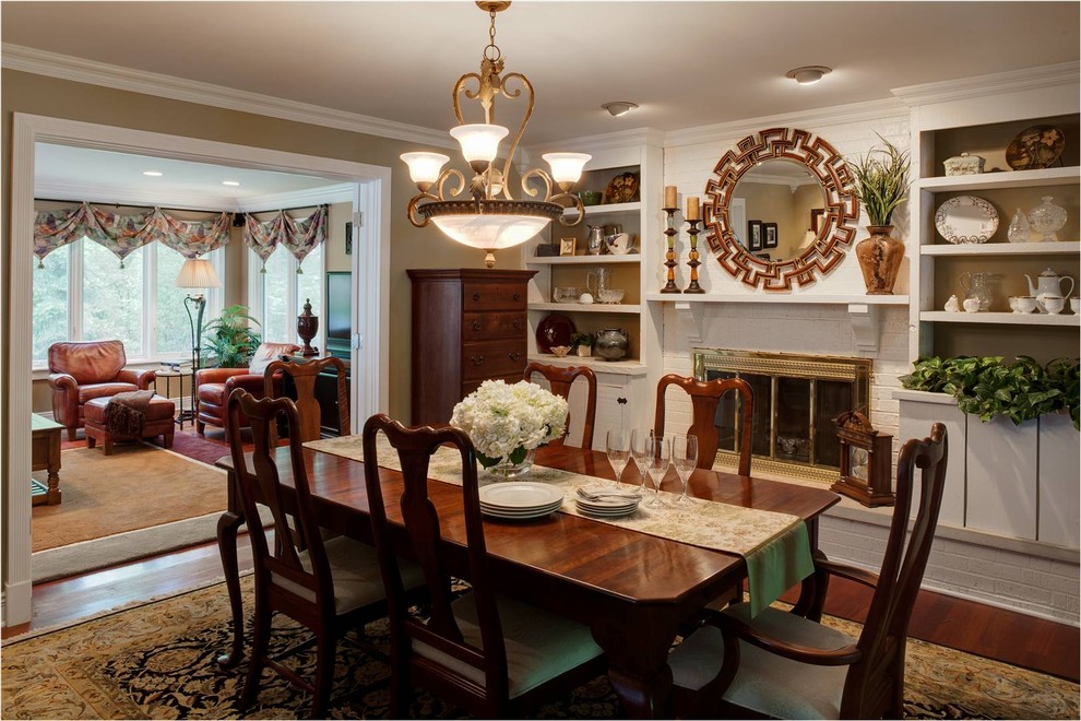 Exemple d'une salle à manger chic fermée et de taille moyenne avec un mur beige, parquet foncé, un manteau de cheminée en brique et éclairage.