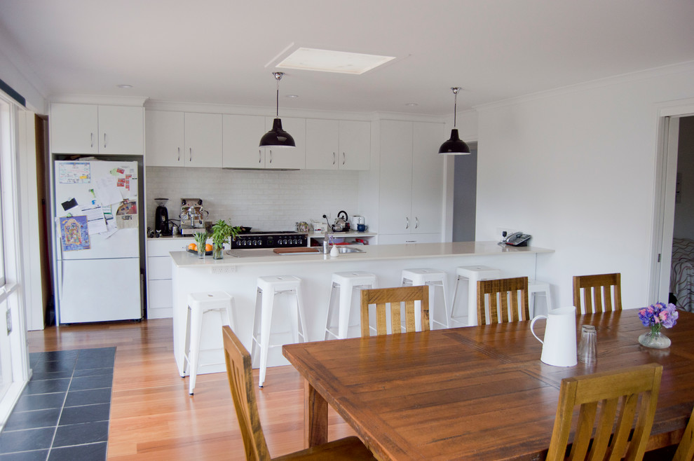 Идея дизайна: кухня-столовая в современном стиле с белыми стенами, полом из бамбука и фасадом камина из камня