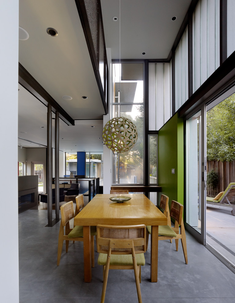 Aménagement d'une salle à manger ouverte sur la cuisine contemporaine avec un mur vert et sol en béton ciré.