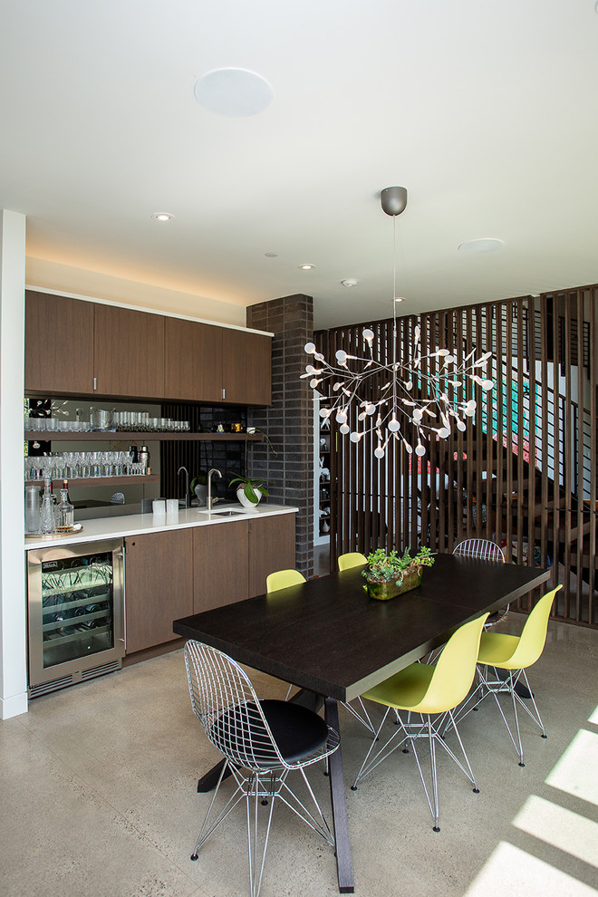 Immagine di una cucina minimalista di medie dimensioni con pavimento in cemento, pavimento grigio, lavello da incasso, ante lisce, ante in legno bruno, elettrodomestici da incasso e top bianco