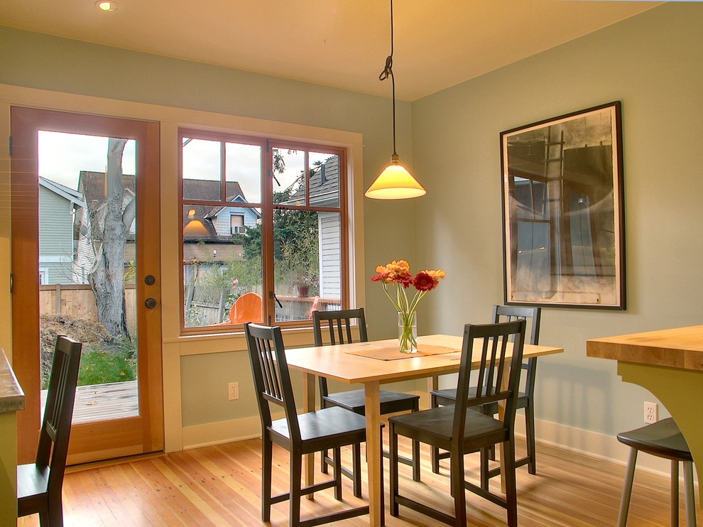 Réalisation d'une petite salle à manger ouverte sur la cuisine craftsman avec un mur vert et un sol en bois brun.