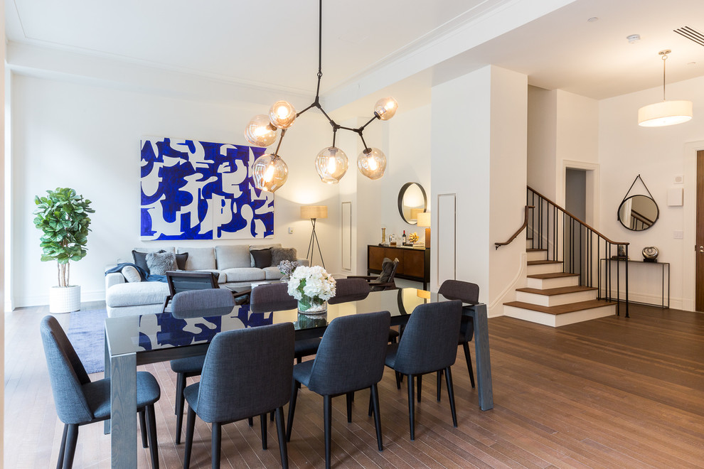 Immagine di una sala da pranzo aperta verso il soggiorno minimal con pareti bianche e pavimento in legno massello medio