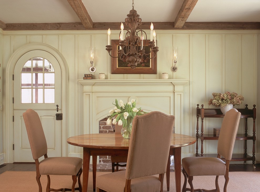 Cette image montre une salle à manger traditionnelle avec un mur beige, une cheminée standard et un manteau de cheminée en brique.