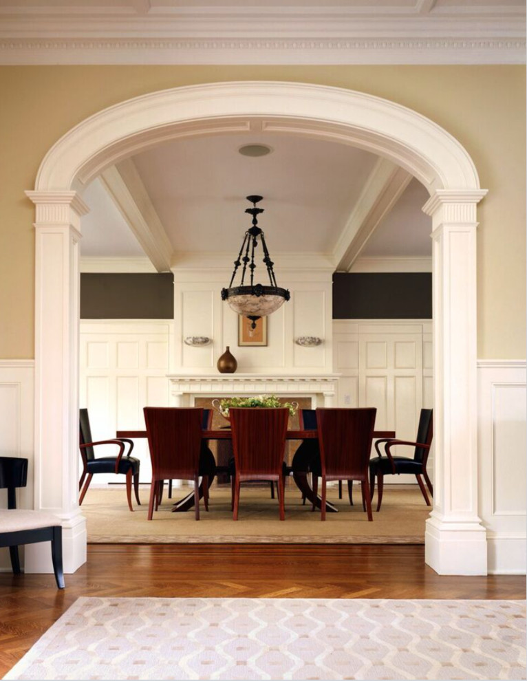 На фото: огромная отдельная столовая в классическом стиле с коричневыми стенами, темным паркетным полом, стандартным камином и фасадом камина из камня с