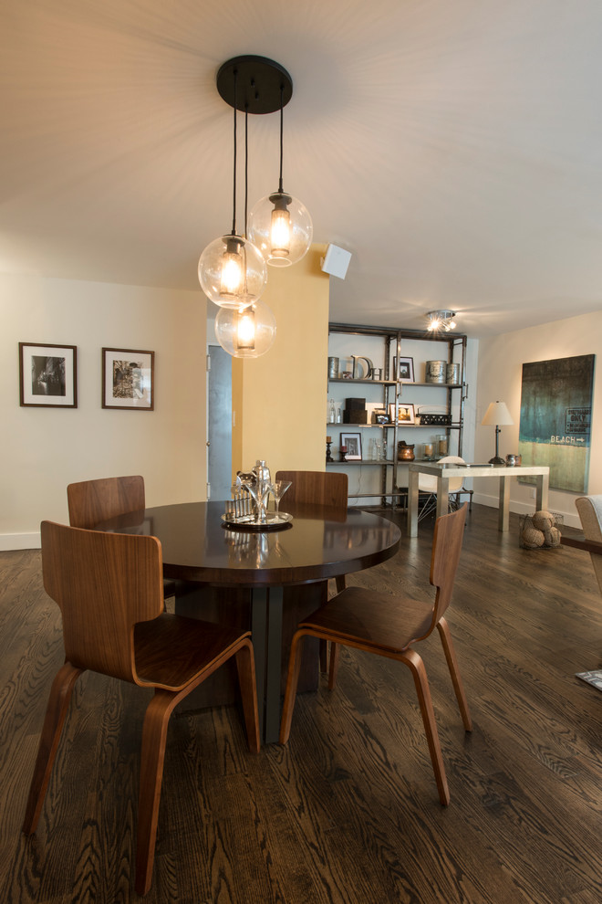 This is an example of an industrial dining room in New York with beige walls and dark hardwood flooring.