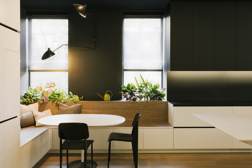 Cette photo montre une grande salle à manger ouverte sur la cuisine tendance avec un mur noir, un sol en bois brun, aucune cheminée et éclairage.