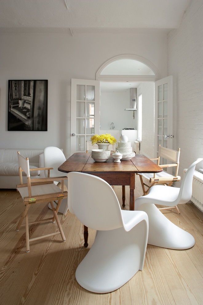 Cette image montre une salle à manger design avec un mur blanc et parquet clair.