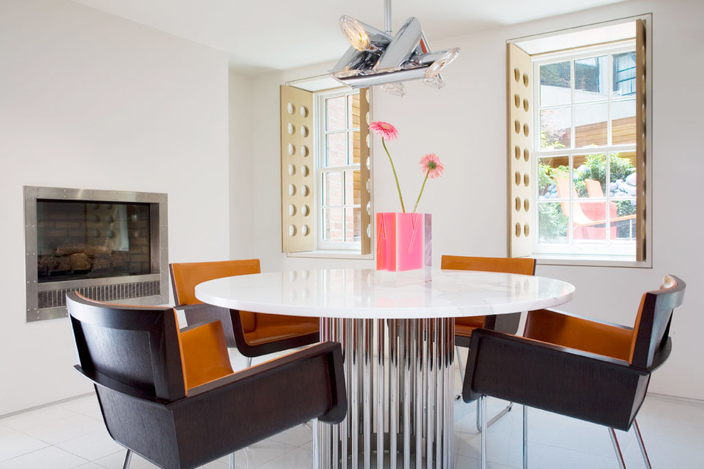 Idée de décoration pour une salle à manger design avec un mur blanc et une cheminée standard.