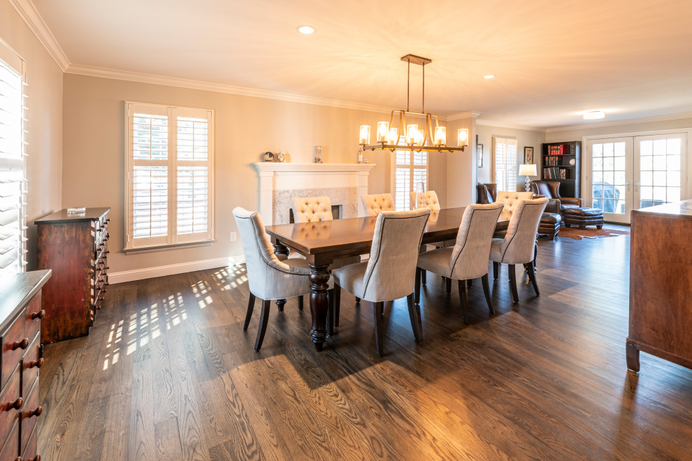 Inspiration pour une grande salle à manger ouverte sur le salon avec un mur gris, un sol en bois brun, une cheminée standard, un manteau de cheminée en bois et un sol marron.