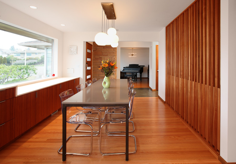 Mid-century modern medium tone wood floor kitchen/dining room combo photo in Seattle with white walls