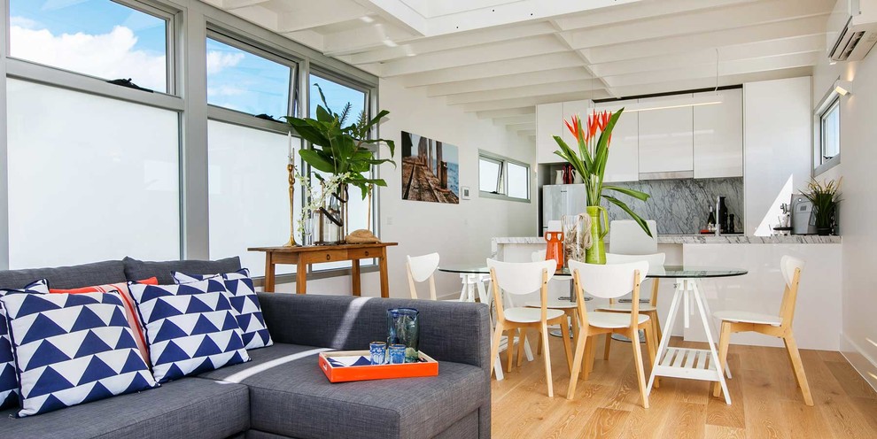 Esempio di una sala da pranzo aperta verso il soggiorno stile marinaro con parquet chiaro e pareti bianche