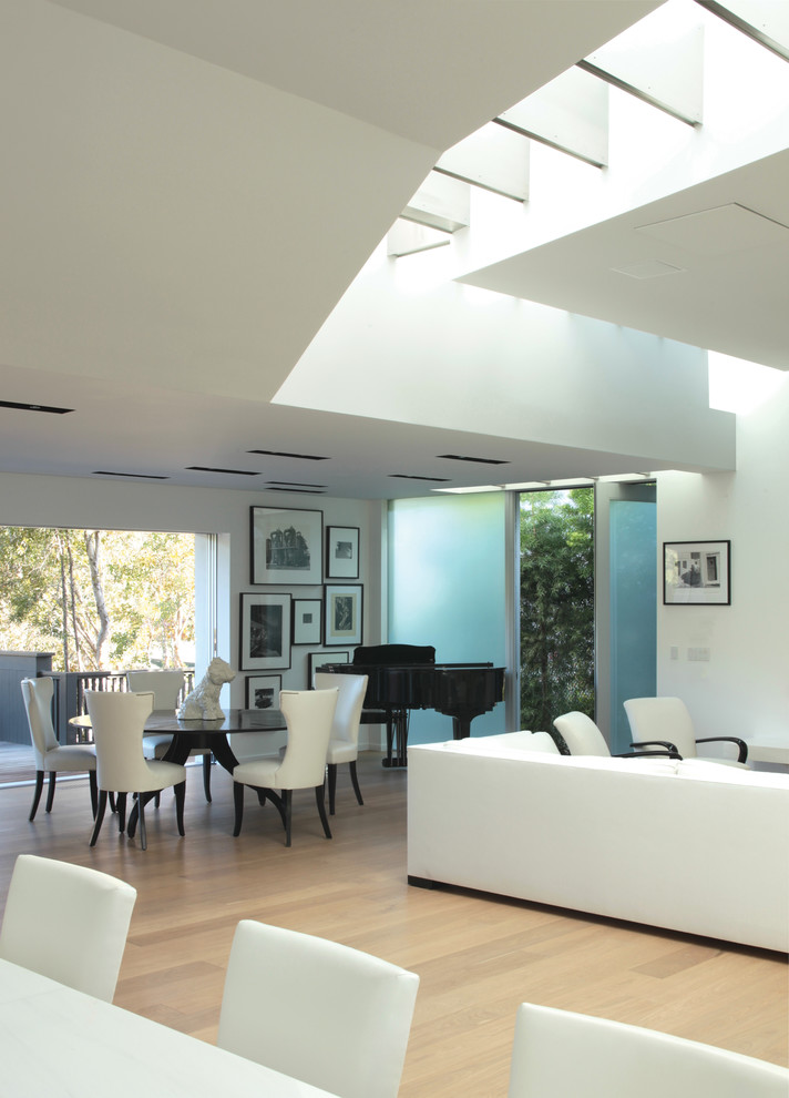 Idee per una sala da pranzo aperta verso il soggiorno minimalista di medie dimensioni con pareti bianche e pavimento in legno massello medio