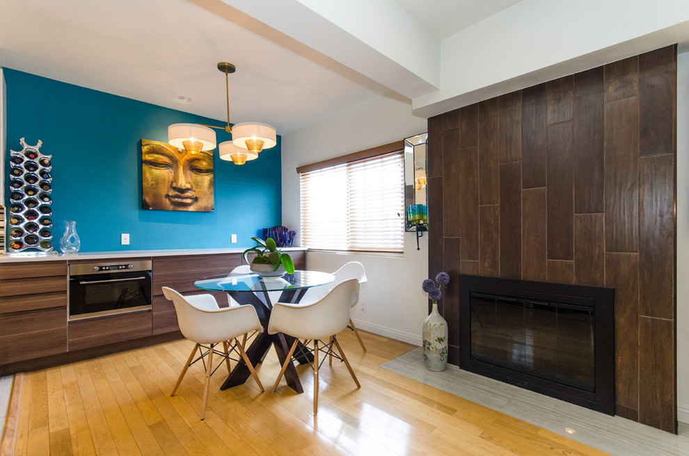 Ejemplo de comedor de cocina contemporáneo con paredes azules, suelo de madera en tonos medios, todas las chimeneas y marco de chimenea de madera