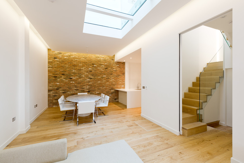 Immagine di una sala da pranzo aperta verso il soggiorno minimal di medie dimensioni con pareti bianche, nessun camino, pavimento marrone e pavimento in legno massello medio