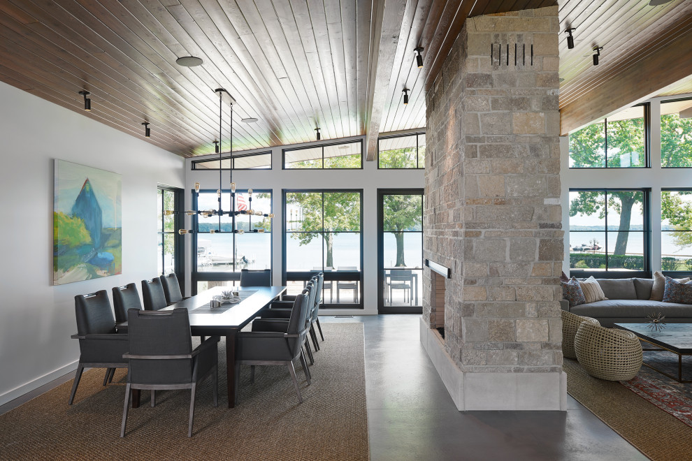 Esempio di un'ampia sala da pranzo aperta verso il soggiorno design con pavimento in cemento, camino bifacciale e pavimento grigio