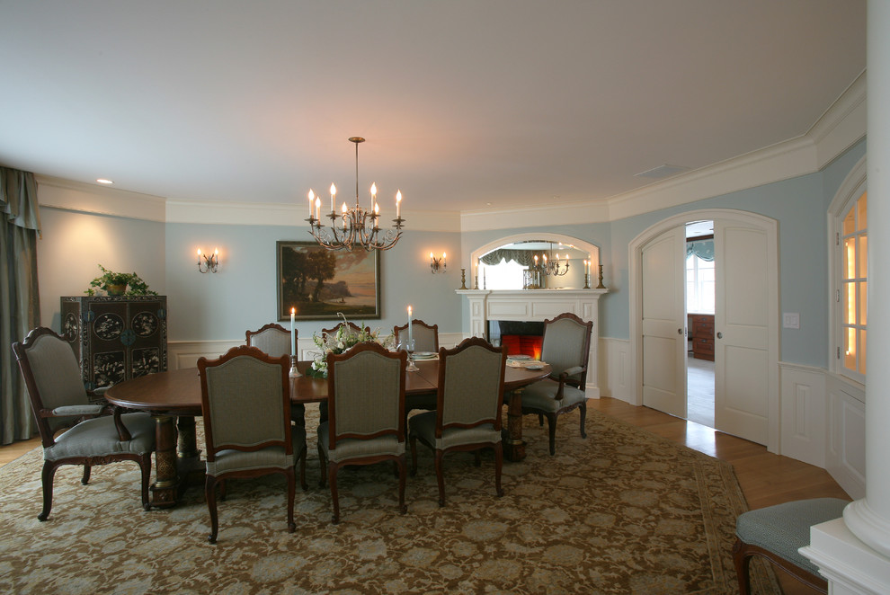 Пример оригинального дизайна: большая отдельная столовая в классическом стиле с синими стенами, светлым паркетным полом, стандартным камином и фасадом камина из штукатурки