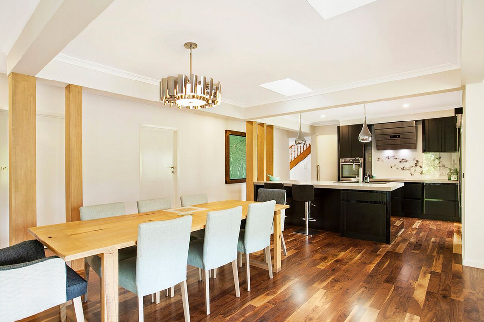 Réalisation d'une grande salle à manger ouverte sur le salon design avec un mur blanc et un sol en bois brun.
