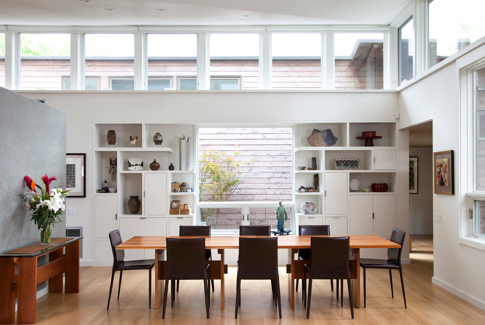 Modelo de comedor minimalista con paredes blancas y suelo de madera en tonos medios