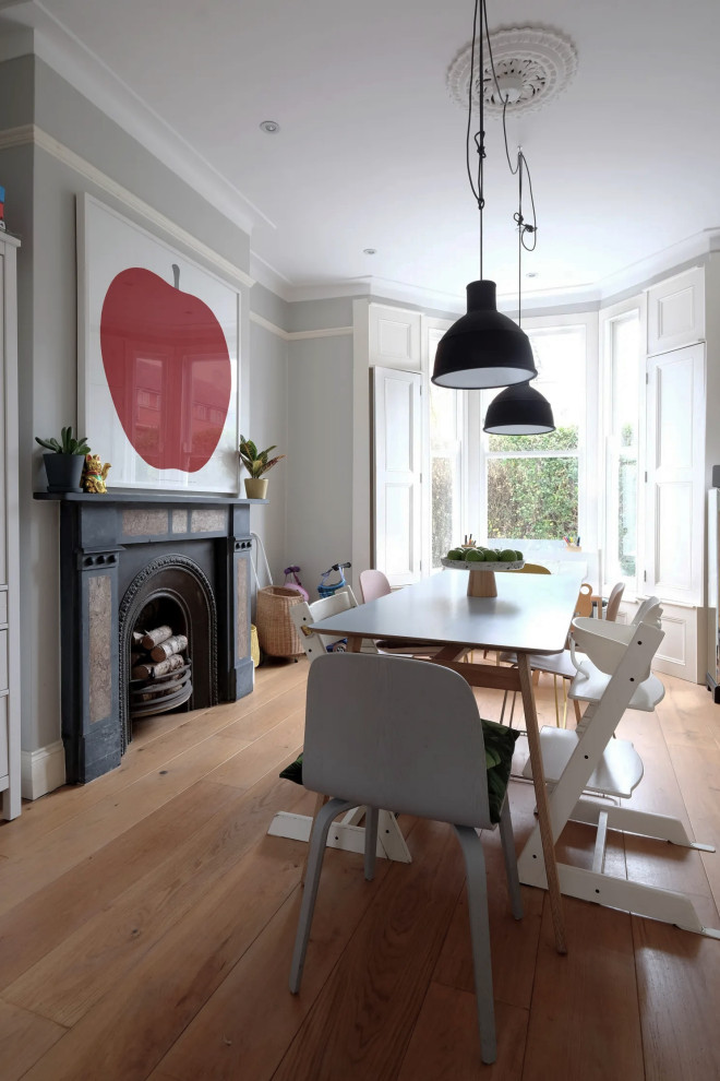 Medium sized scandi open plan dining room in London with grey walls, light hardwood flooring, a standard fireplace, a stone fireplace surround and brown floors.