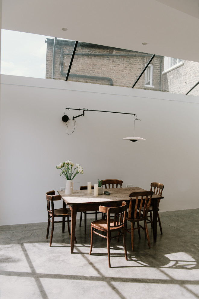 Medium sized industrial dining room in London with white walls, concrete flooring and grey floors.