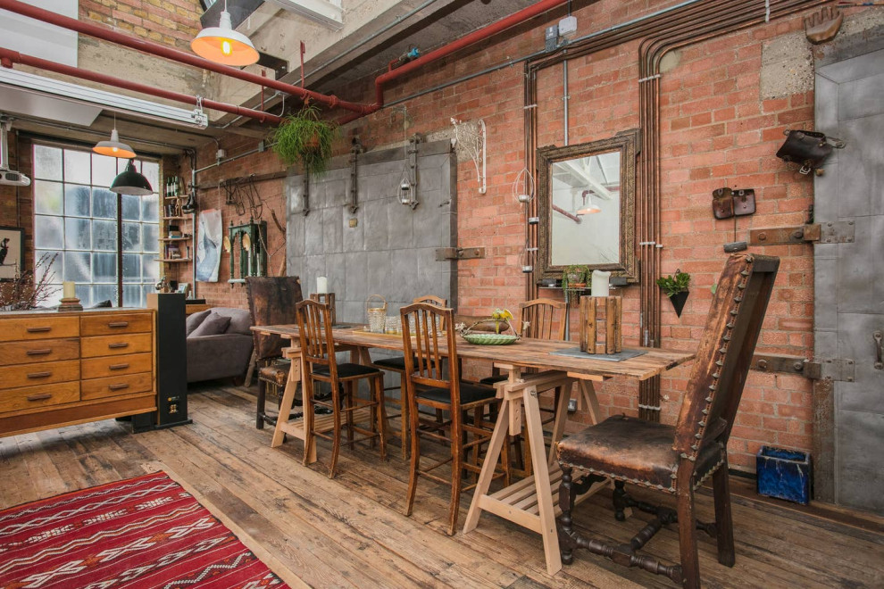 Design ideas for an industrial dining room in London with red walls, medium hardwood flooring and brown floors.