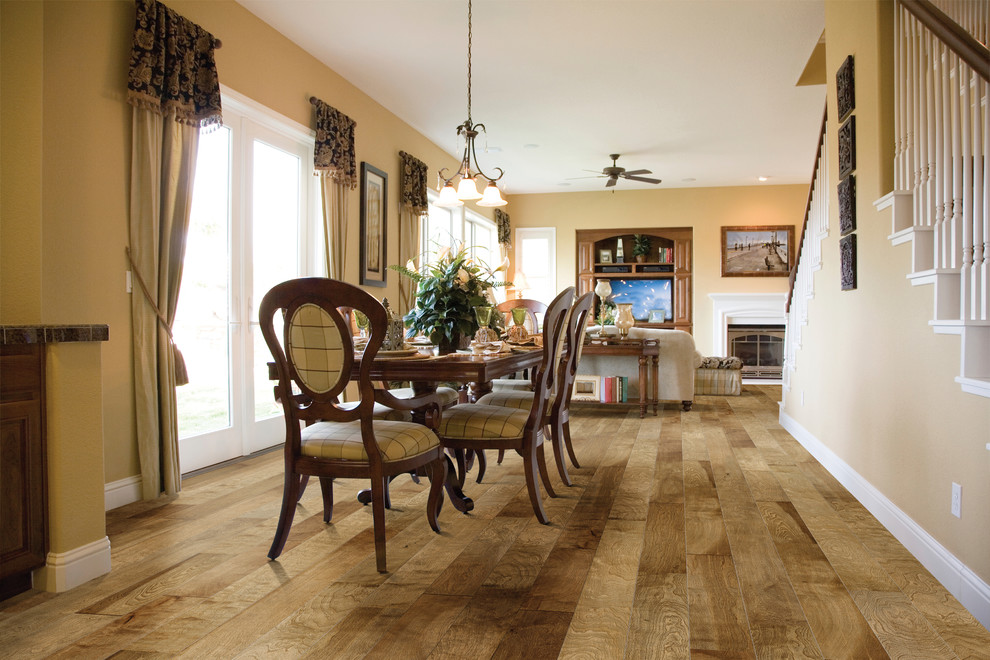 Immagine di una sala da pranzo aperta verso la cucina classica di medie dimensioni con pareti beige, pavimento in legno massello medio, camino classico e cornice del camino in legno